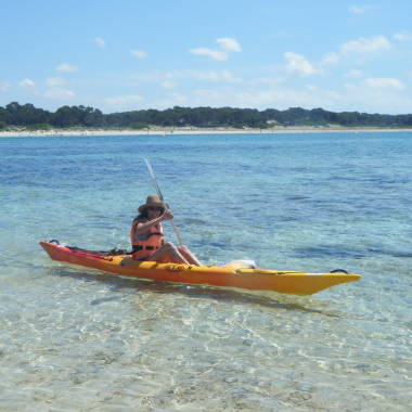 Persona utilizando un kayak en la playa